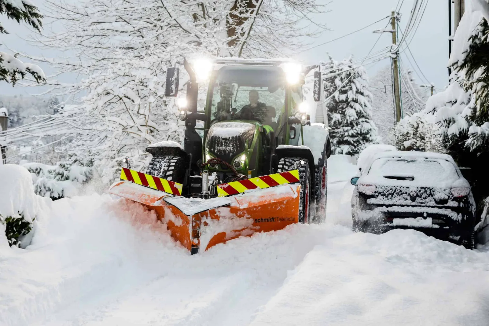 Traktor med brøyteskjær i snødekt område